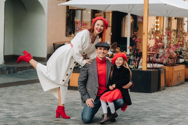 Foto una elegante familia de tres pasea por la ciudad otoñal posando para un fotógrafo papá, mamá e hija en la ciudad otoñal