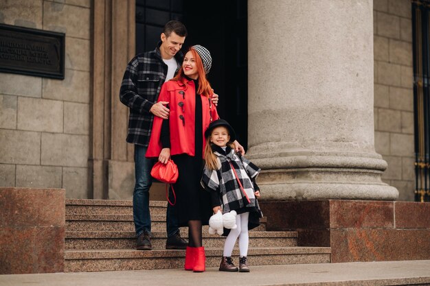 Foto una elegante familia de tres pasea por la ciudad otoñal posando para un fotógrafo papá, mamá e hija en la ciudad otoñal