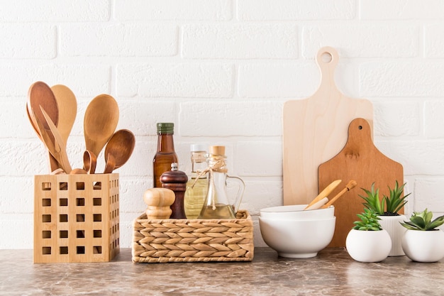 Elegante fondo blanco de cocina con utensilios de cocina y plantas de interior en macetas verdes sobre una encimera de mármol