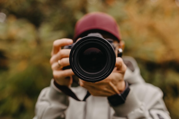 Elegante fotógrafo barbudo con una cámara en las manos toma una foto en el parque de otoño