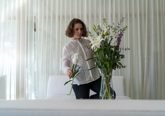 Elegante Frau arrangiert Blumen in einem gemütlichen weißen Zimmer