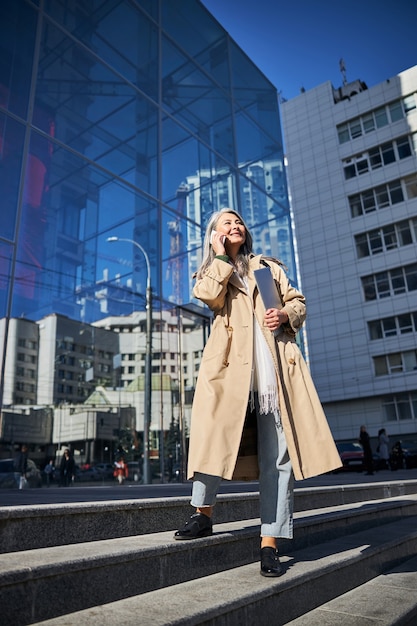 Elegante Frau, die auf der Straße mit dem Handy spricht