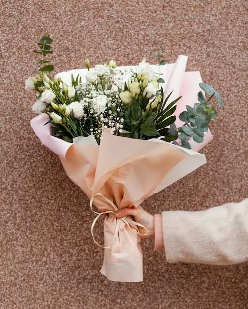 Foto elegante frau, die blumenstrauß draußen in der stadt hält