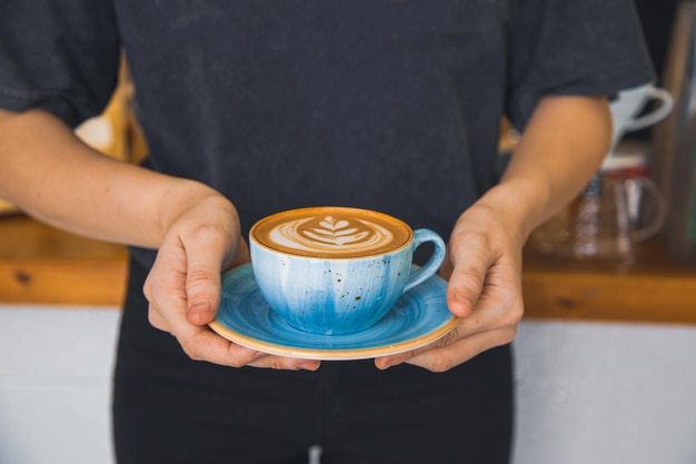 Elegante Frau hält einen kunstvoll gestalteten Kaffee Latte in der Hand