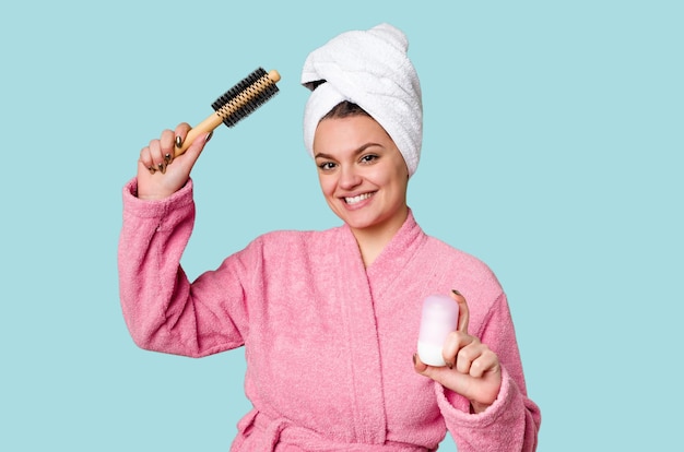 Elegante Frau in einem rosafarbenen Bademantel, bereit für den Tag mit Haarbürste und Deodorant