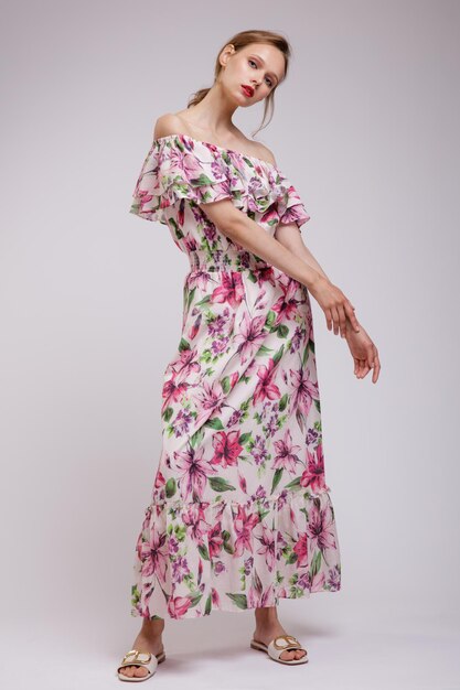 Elegante Frau in hübschem langem Kleid mit floralen Mustern in roter Farbe auf weißem weichem grauem Hintergrund