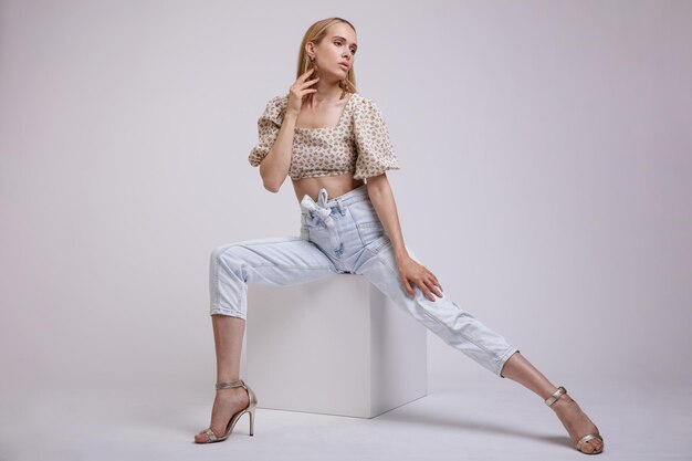 elegante Frau in hübschen blauen Jeans, beige mit Blumenmuster oben auf weißem Hintergrund