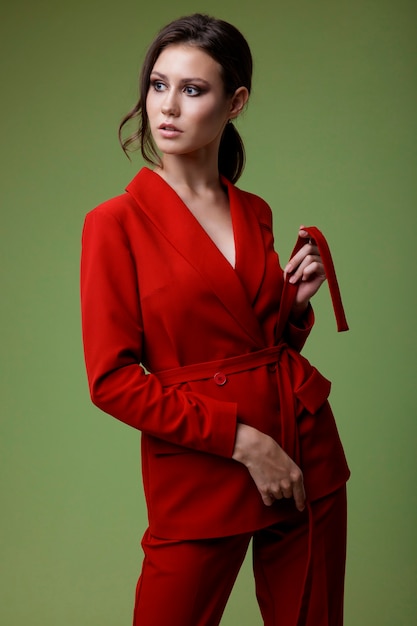 Elegante Frau in roter Anzugjacke Hose auf grünem Hintergrund Studio Shot Geschäftsfrau