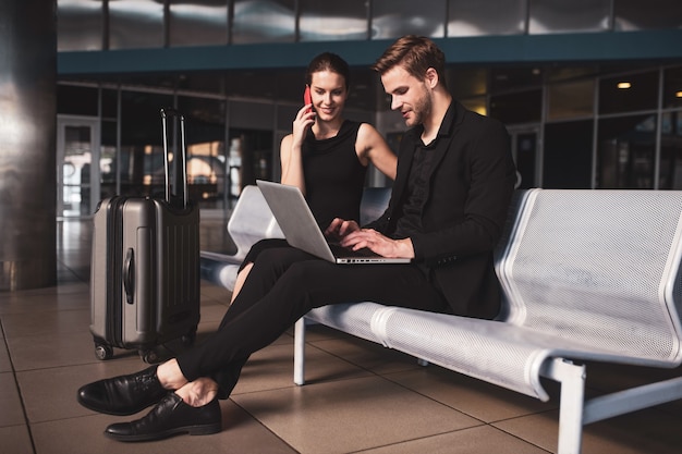 Elegante Frau und Mann arbeiten an einem Laptop am Flughafen