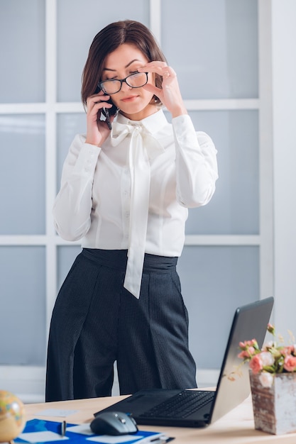 Elegante Geschäftsfrau, die am Telefon im Büro spricht.