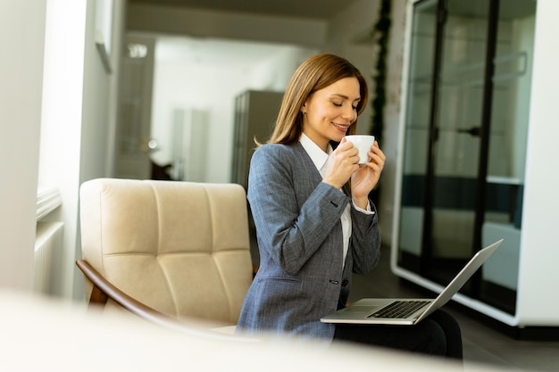 Elegante Geschäftsfrau genießt einen ruhigen Kaffeenaufenthalt an einem sonnigen Büromorgen