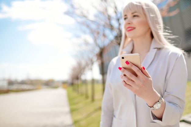 Elegante Geschäftsfrau in der Sonnenbrille mit Telefon. Geschäftsfrau mit Telefon nahe Büro.