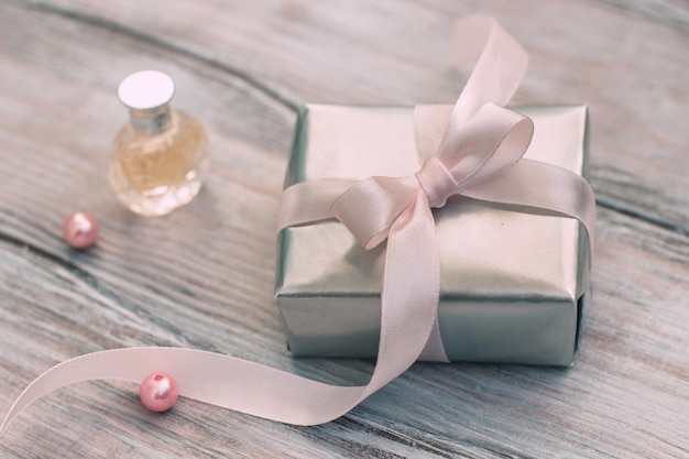 Elegante Geschenkbox aus Silberpapier mit rosa Schleife und Parfüm