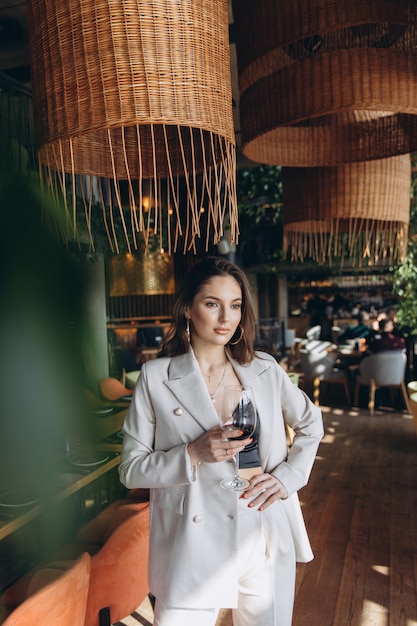 Elegante y glamurosa mujer con copa de vino tinto en restaurante.