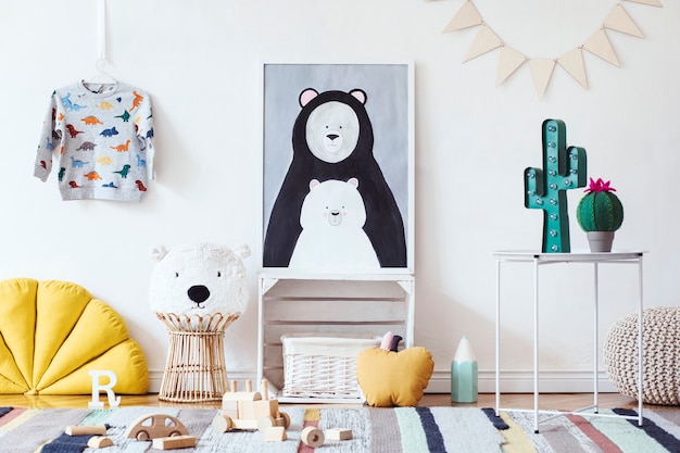 Elegante habitación infantil escandinava con póster, juguetes, osito de peluche, animal de peluche, puf natural y accesorios para niños.