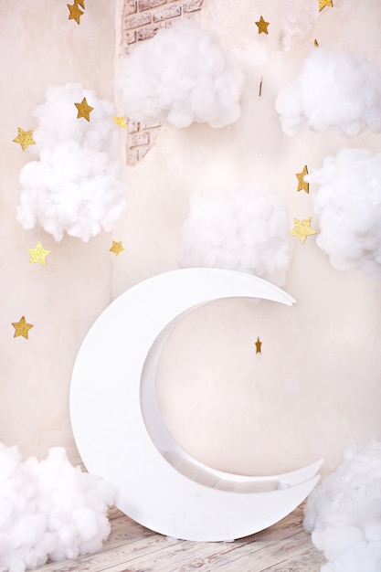 Elegante habitación infantil vintage con una luna de madera y nubes textiles. Ubicación de los niños para una sesión de fotos. Luna con estrellas y nubes decoración de ensueño. Elegante habitación infantil vintage con luna de madera