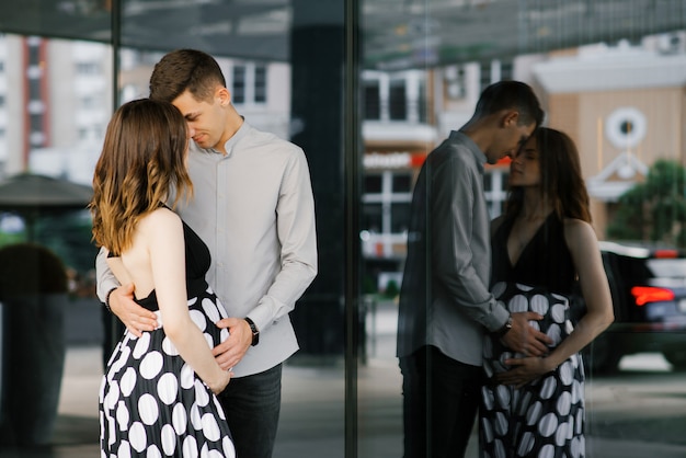 Elegante hermosa pareja de enamorados embarazadas en ropa de blanco y negro abrazo