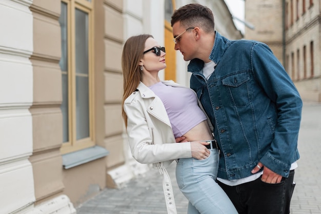 Elegante hermosa pareja de moda hombre y mujer con gafas de sol vintage en ropa casual de mezclilla de moda abrazo en la ciudad