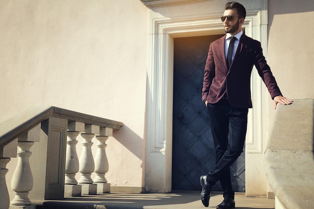 Elegante hombre de moda con gafas de sol negras posando al aire libre en el espacio de copia de escaleras