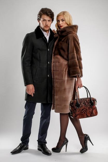 Elegante hombre y mujer glamour en abrigo de piel posando con traje de invierno.