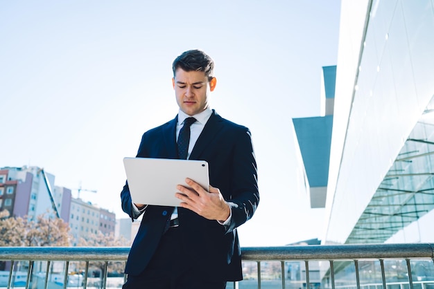 Elegante hombre de negocios con tableta sobre fondo urbano