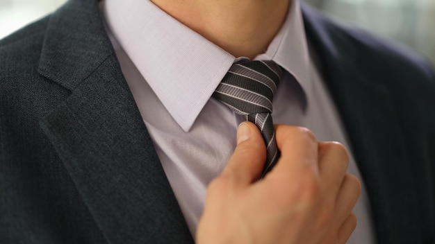Foto elegante hombre de negocios en traje de enderezar la corbata en primer plano de la camisa