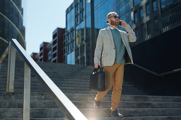 Elegante hombre de negocios usando el teléfono en movimiento