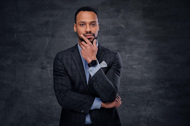 Un elegante hombre negro americano vestido con un traje de fondo gris.