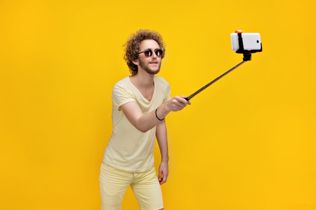 Elegante hombre de pelo rizado tomando selfie con monopie