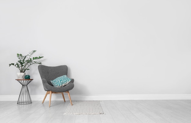 Elegante interior de habitación con cómodo sillón y planta cerca de la pared blanca Espacio para texto