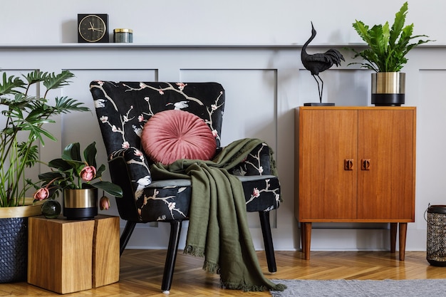 Elegante interior de sala de estar con sillón de diseño, inodoro retro, muchas plantas en maceta, pared gris, decoración, alfombra, reloj y accesorios personales en una decoración elegante para el hogar.