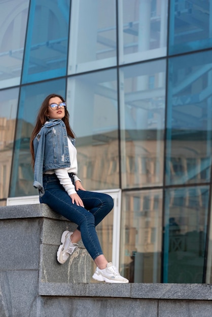 Elegante jovem ao lado da construção de óculos Jovem mulher no dia ensolarado da rua da cidade