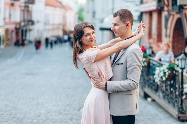 Elegante jovem casal apaixonado andando na rua ao pôr do sol