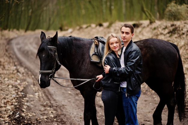 Elegante jovem casal apaixonado perto de cavalo na floresta de outono