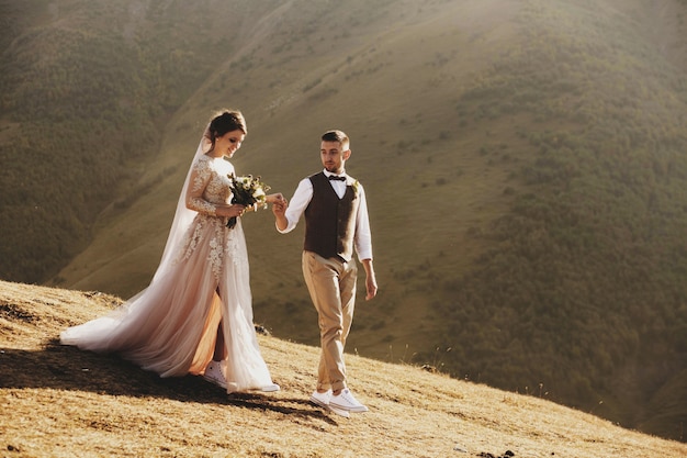 Elegante jovem casal de noivos se diverte posando em belas montanhas da Geórgia