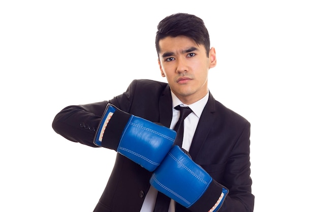 Elegante jovem com cabelo preto na camisa branca e smoking com gravata preta e luvas de boxe azuis