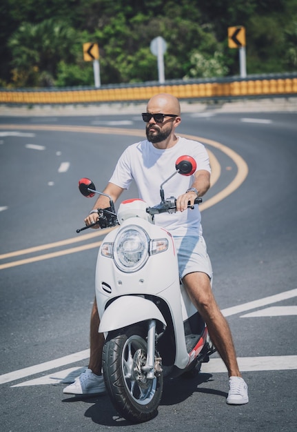 Elegante jovem com sua moto na estrada