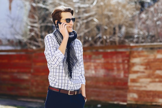 Elegante jovem em óculos de sol com telefone na rua