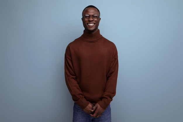 Elegante jovem empresário africano moreno em elegante suéter marrom e óculos no estúdio