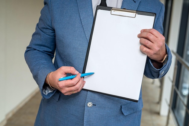 Elegante jovem empresário em um terno clássico e camisa branca segurando um tablet e caneta Conceito de empresário