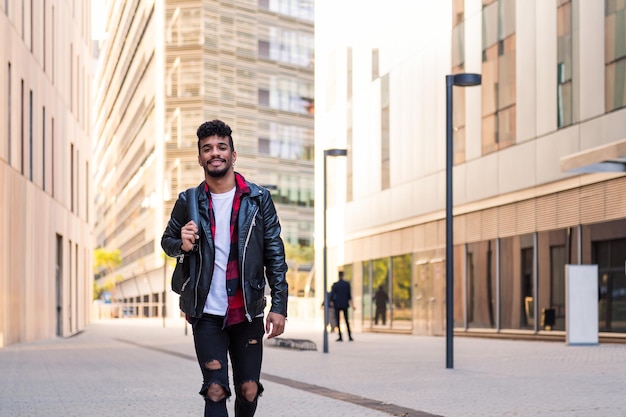 Elegante jovem latino andando feliz pela cidade com sua mochila, conceito de estilo de vida urbano