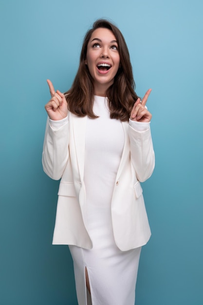 Elegante jovem morena com cabelo comprido mulher de vestido branco aponta o dedo para o lado