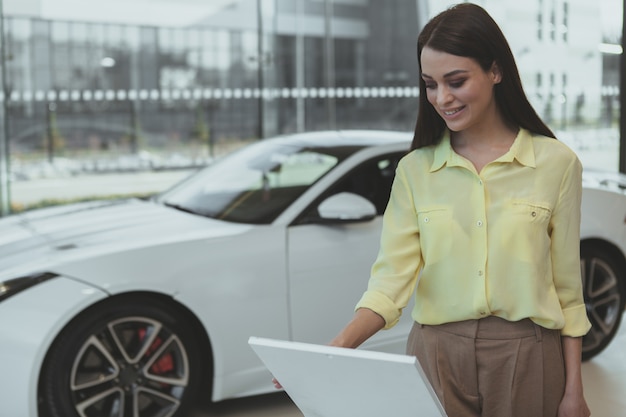 Elegante joven compra coche nuevo en concesionario