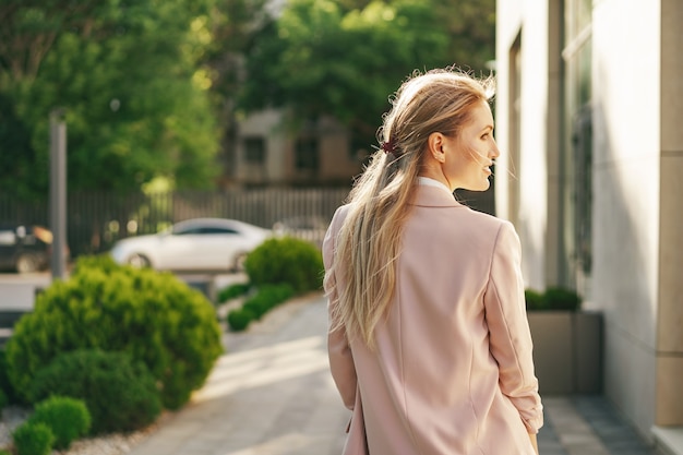 Elegante joven empresaria caminando por las calles de la ciudad en un día soleado