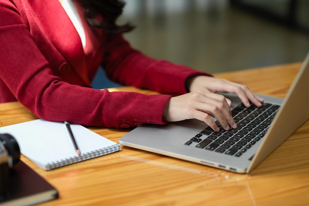 Una elegante joven empresaria trabaja en su computadora portátil, escribiendo en el teclado y enviando un correo electrónico comercial. Imagen recortada