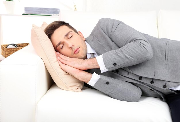 Elegante joven empresario durmiendo en el sofá en casa