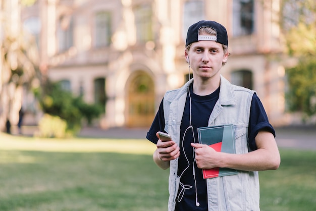 Elegante joven estudiante con gorra cerca de la universidad