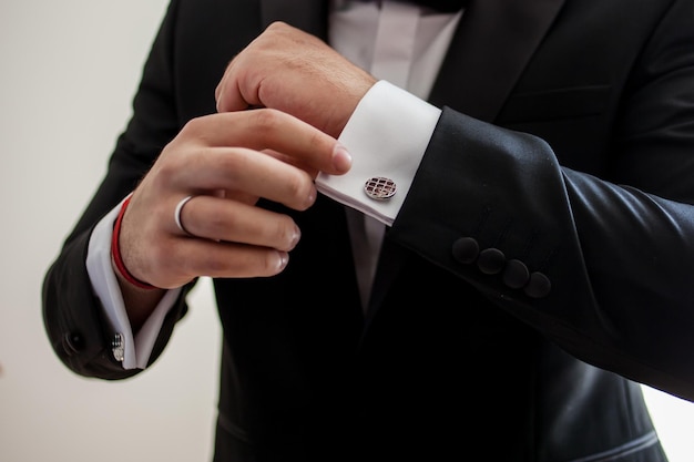 Elegante joven hombre de moda mirando sus gemelos mientras los arregla. el novio está listo para la boda