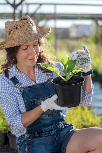 Elegante joven jardinero sosteniendo una planta antes de plantar en el jardín