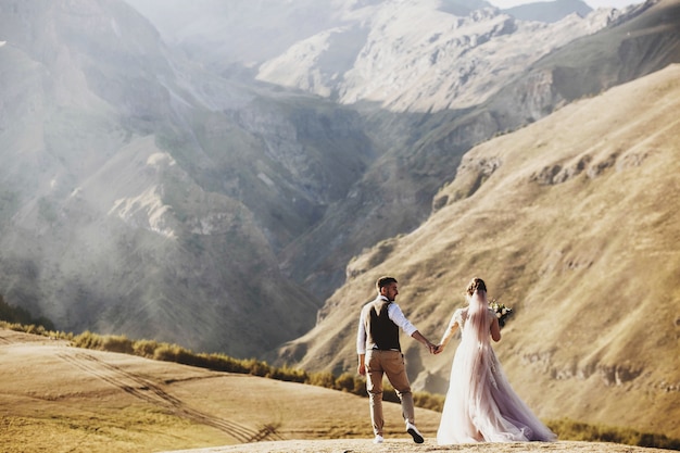 Elegante joven pareja se divierte posando en las hermosas montañas georgianas